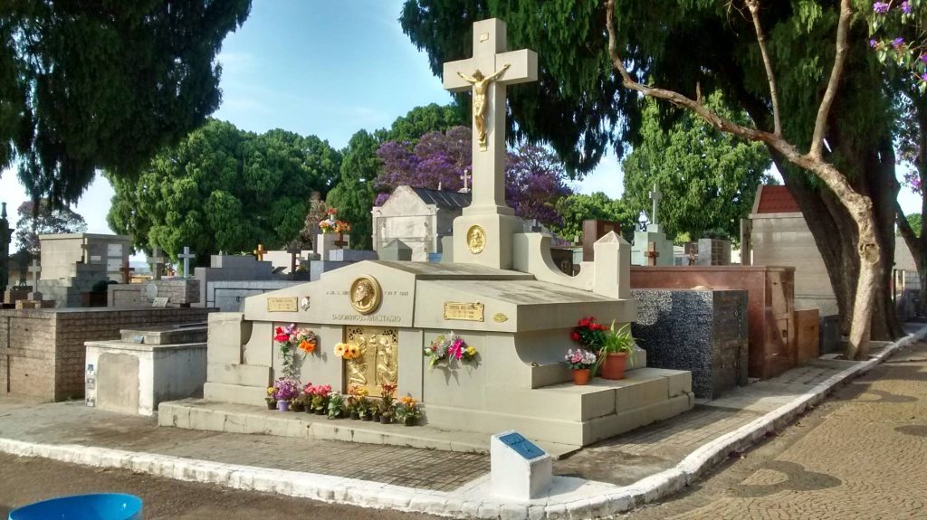 Foto colorida do túmulo de Domingos Anastácio no Cemitério Nossa Senhora do Desterro. O túmulo está com alguns vasos de flores, de visitantes.