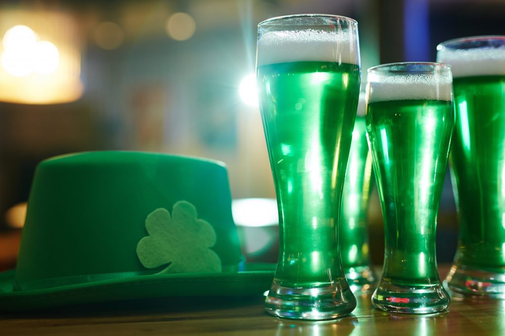 foto de copos com cerveja verdes e um chapeu verde com um trevo, simbolos tipicos de um saint patrick's day