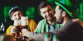 3 homens vestidos de verde e brindando com cervejas em comemoração ao saint patrick's day