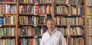 Professor e escritor bauruense José Reginaldo Furtado e uma estante de livros no fundo