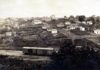 Na publicação sobre a história da Vila Falcão, foto de Bauru antigamente, em preto e branco, com casas antigas e vagão de trem.