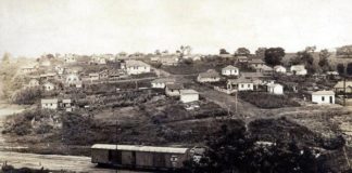 Na publicação sobre a história da Vila Falcão, foto de Bauru antigamente, em preto e branco, com casas antigas e vagão de trem.