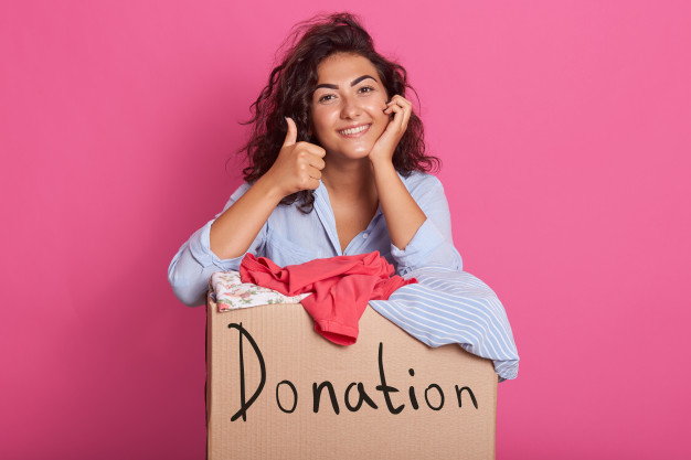 Mulher com uma caixa de roupas para doação. Campanhas de doação para ajudar a população de Bauru no inverno