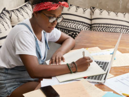 Na foto, uma jovem estudando com livros e computador. Conteúdo sobre cursinho pré-vestibular gratuito em Bauru.