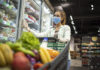 Supermercados em Bauru: centenas de opções no setor atendem consumidores pela cidade Supermercados em Bauru: mulher, de máscara, fazendo compras com carrinho cheio de alimentos.