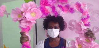 Na foto, uma mulher segundo um arco rosa, participando das ações do Outubro Rosa em Bauru