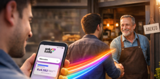 Como anunciar minha empresa na Solutudo? Cliente segura um celular com o aplicativo da Solutudo aberto enquanto um feixe de luz conecta a busca digital ao atendimento presencial em uma empresa local.