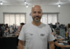O que é a Solutudo e como funciona a plataforma? Integrante da Solutudo em primeiro plano com equipe trabalhando ao fundo no escritório.