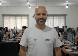 O que é a Solutudo e como funciona a plataforma? Integrante da Solutudo em primeiro plano com equipe trabalhando ao fundo no escritório.